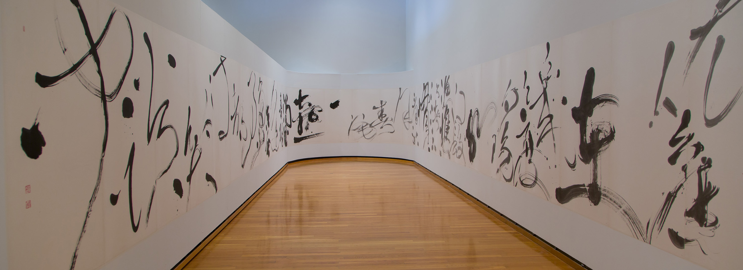 A large Chinese calligraphic scroll wraps around a U shaped gallery wall