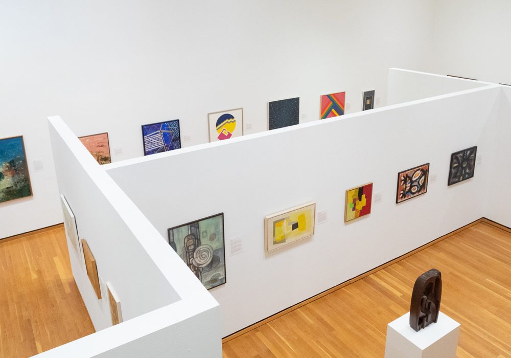 Looking down on an exhibition gallery with white walls and colorful abstract paintings