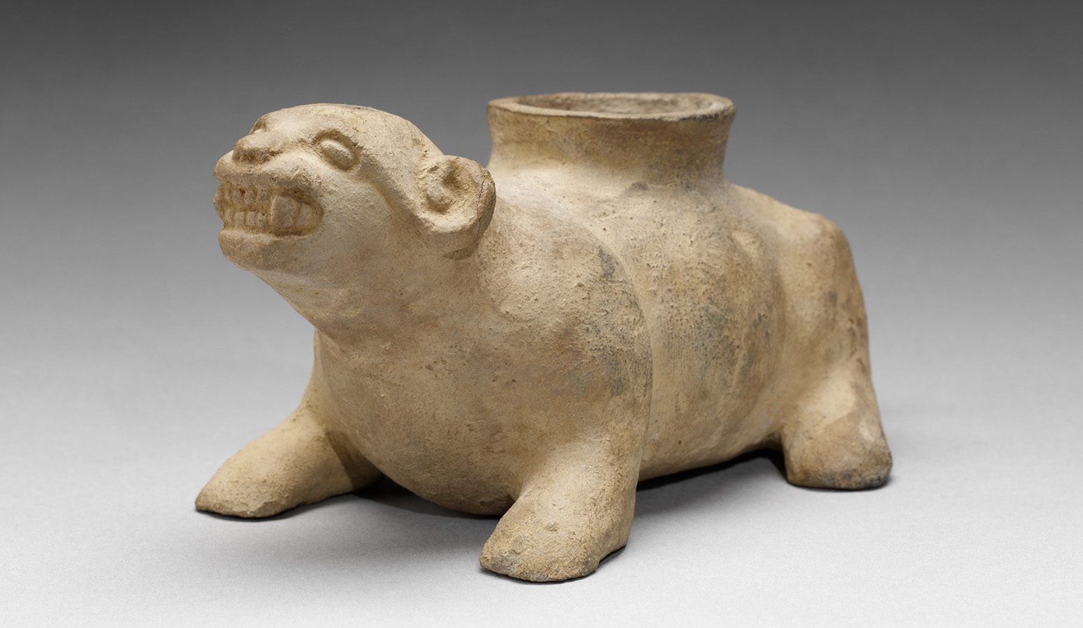 A clay sculpture of a snarling animal on all four legs with a hump on its back