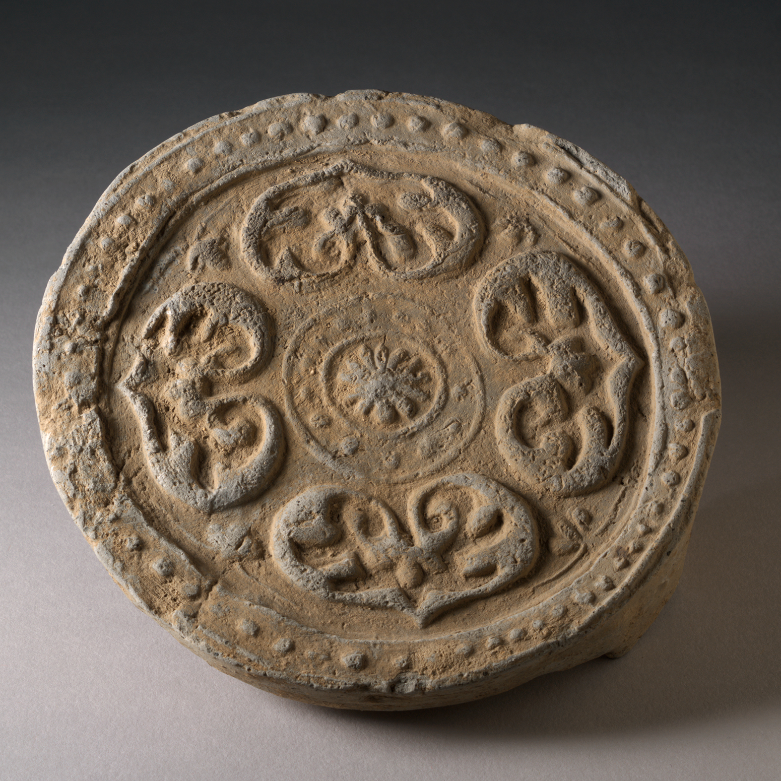 A round brown disc with an incised decorative design