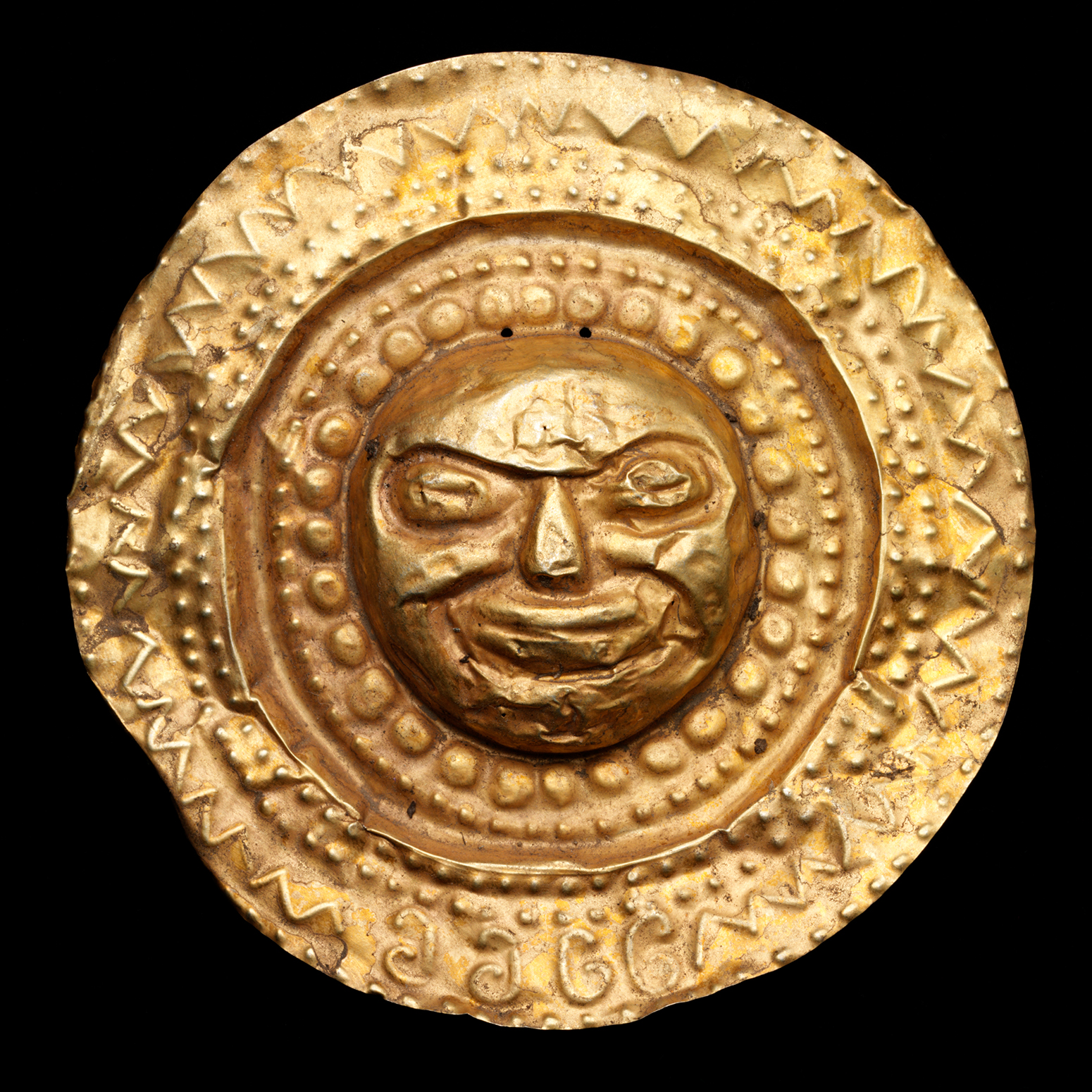 A gold medallion with a small face at the center