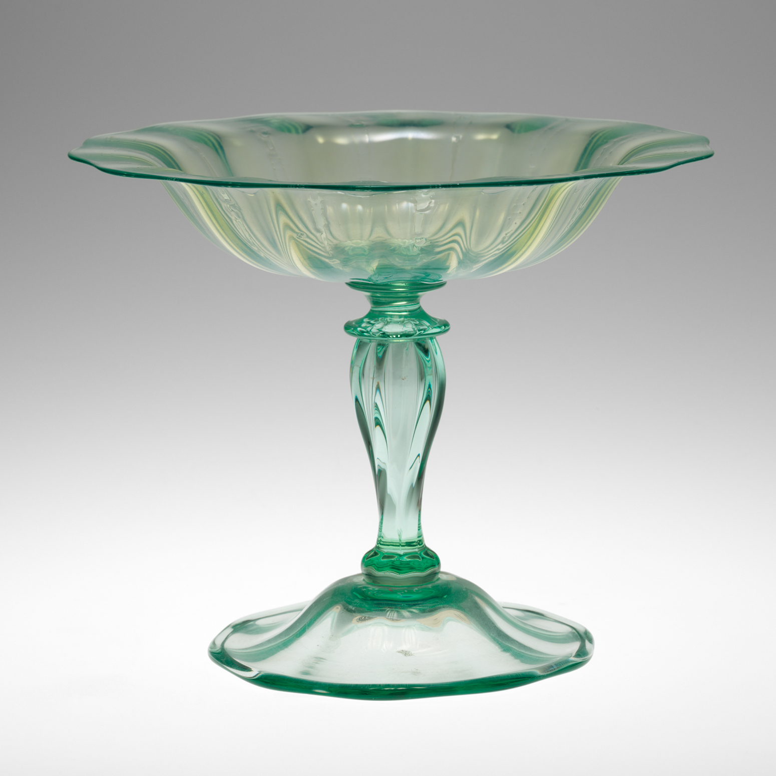 A light green glass dish with a wide rim and tall stem