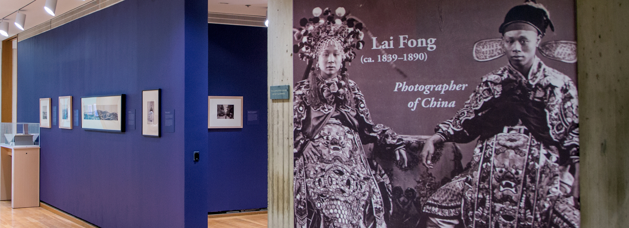 A photography exhibition gallery with purple painted walls and a large photo display of a Chinese man and woman in formal dress