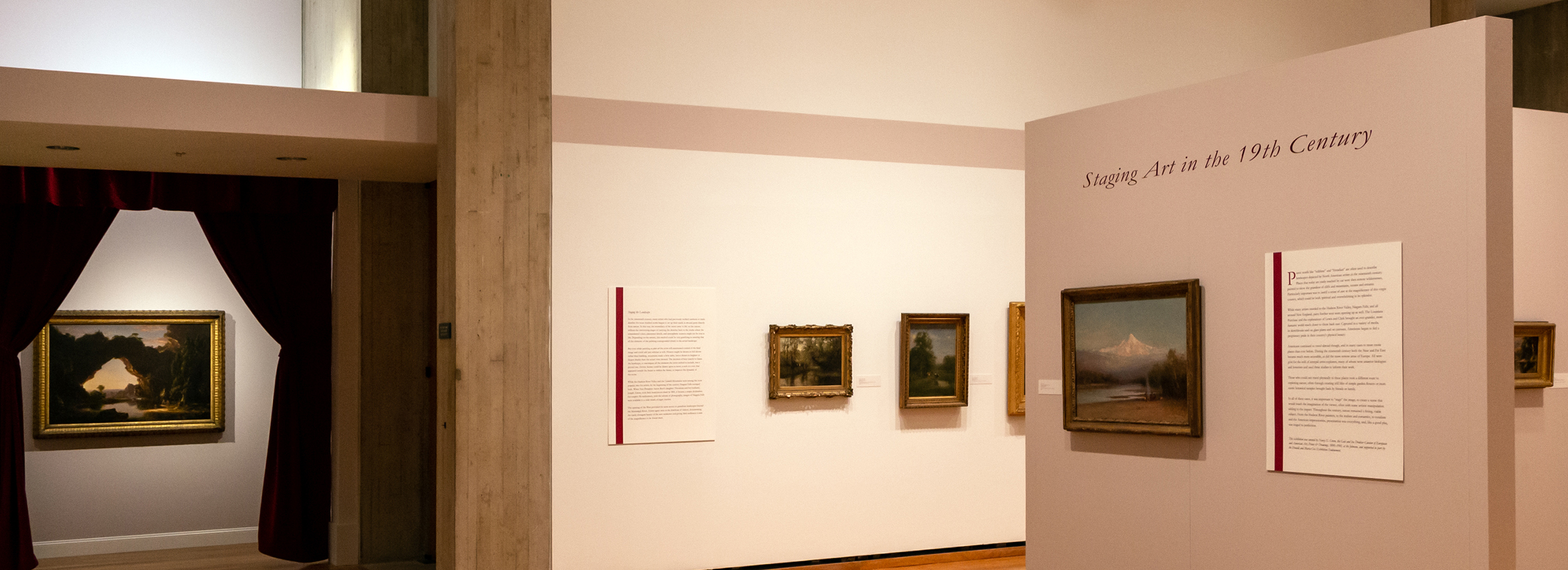 A museum exhibition gallery with several oil paintings and an alcove framed by dark red curtains