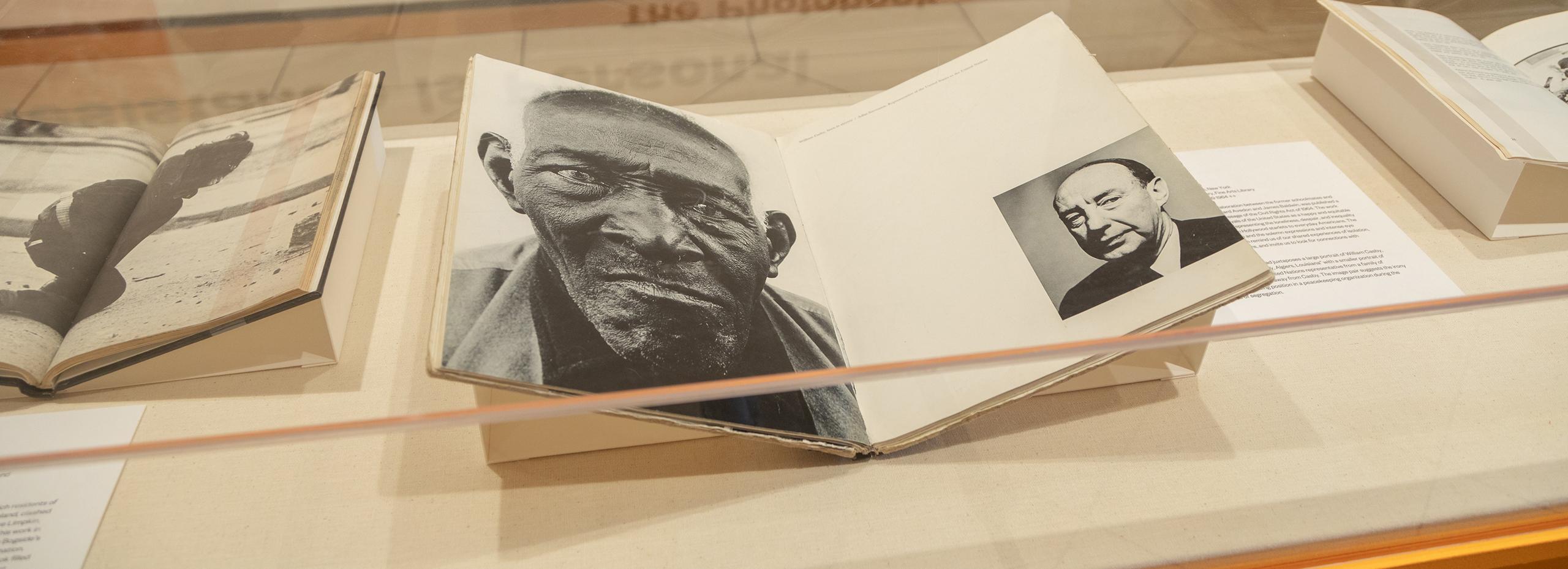 Open books of black and white photography are displayed in a case