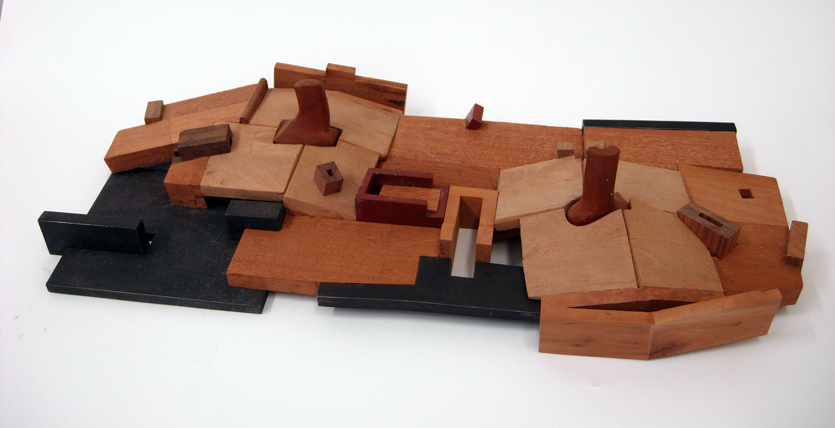 Different shapes of brown and black wood blocks form a landscape-like sculpture