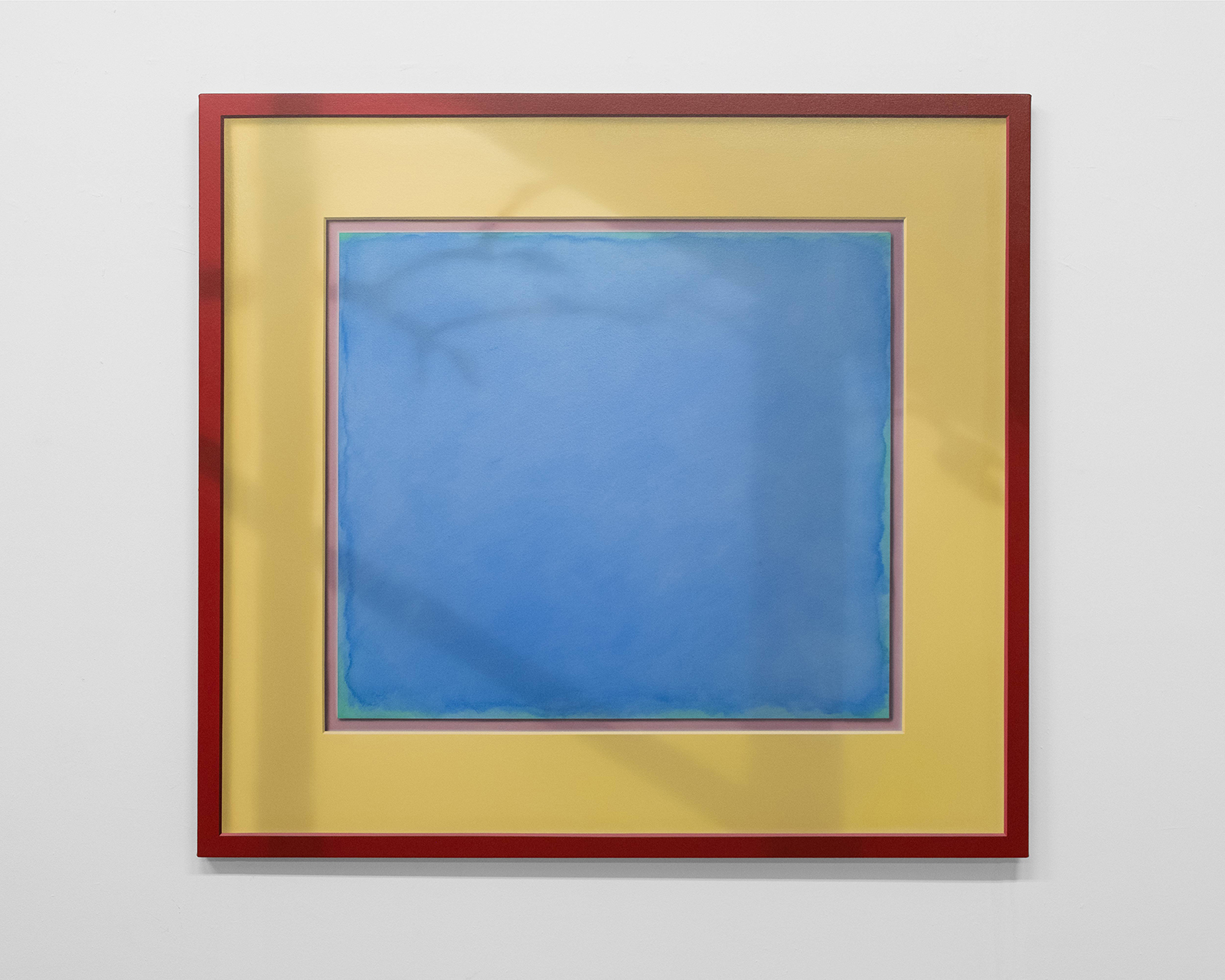 A square red frame, a square yellow mat, and a square blue painting