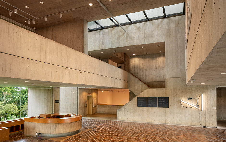 A concrete-walled lobby with windows, a tiled floor, and a circular desk