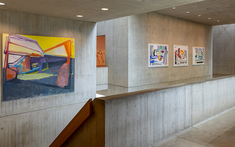 A museum interior space with paintings and concrete walls and stairs