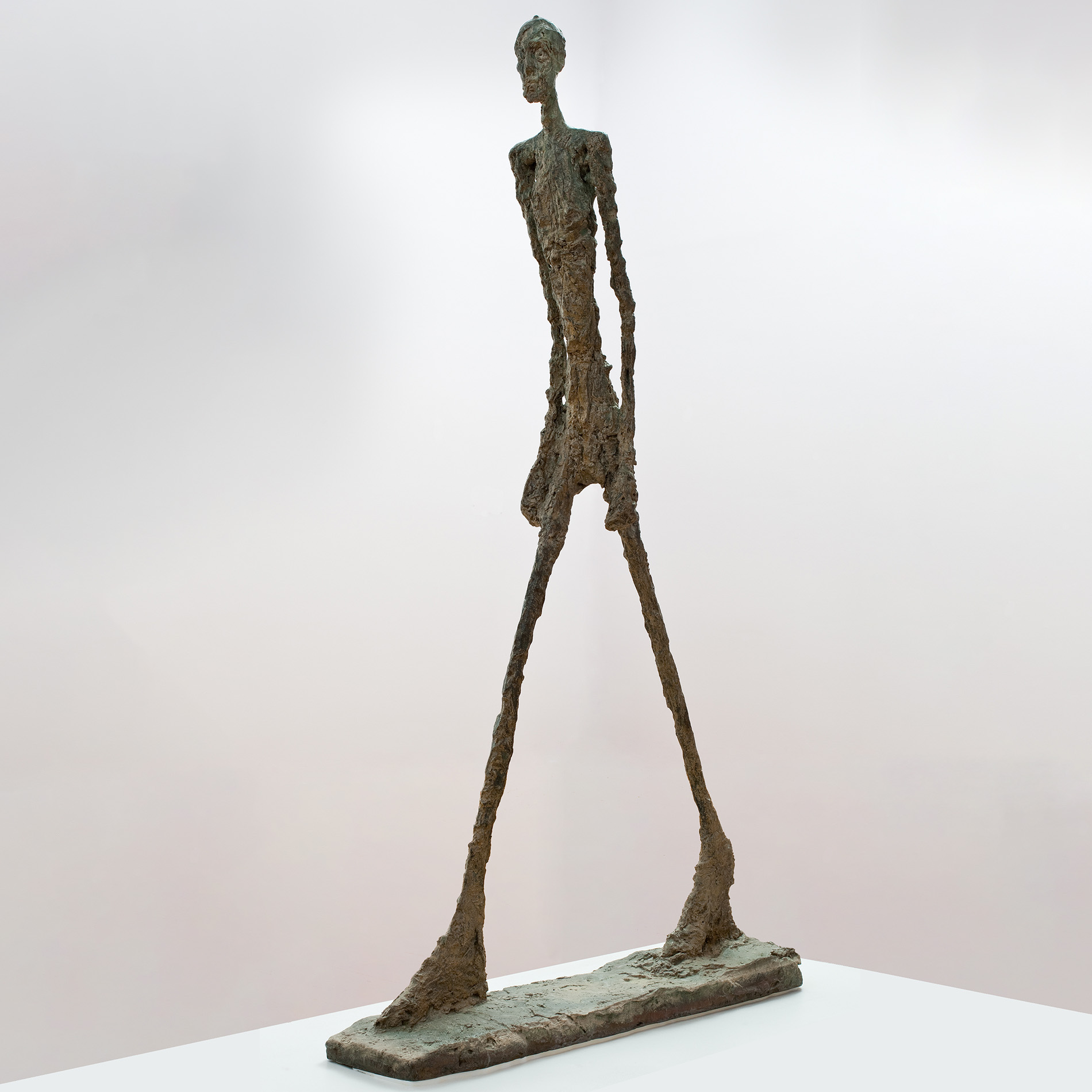A figural sculpture with long arms and legs appears to stride forward