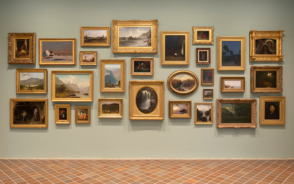 A large green wall with oil paintings in gold frames above a tiled floor