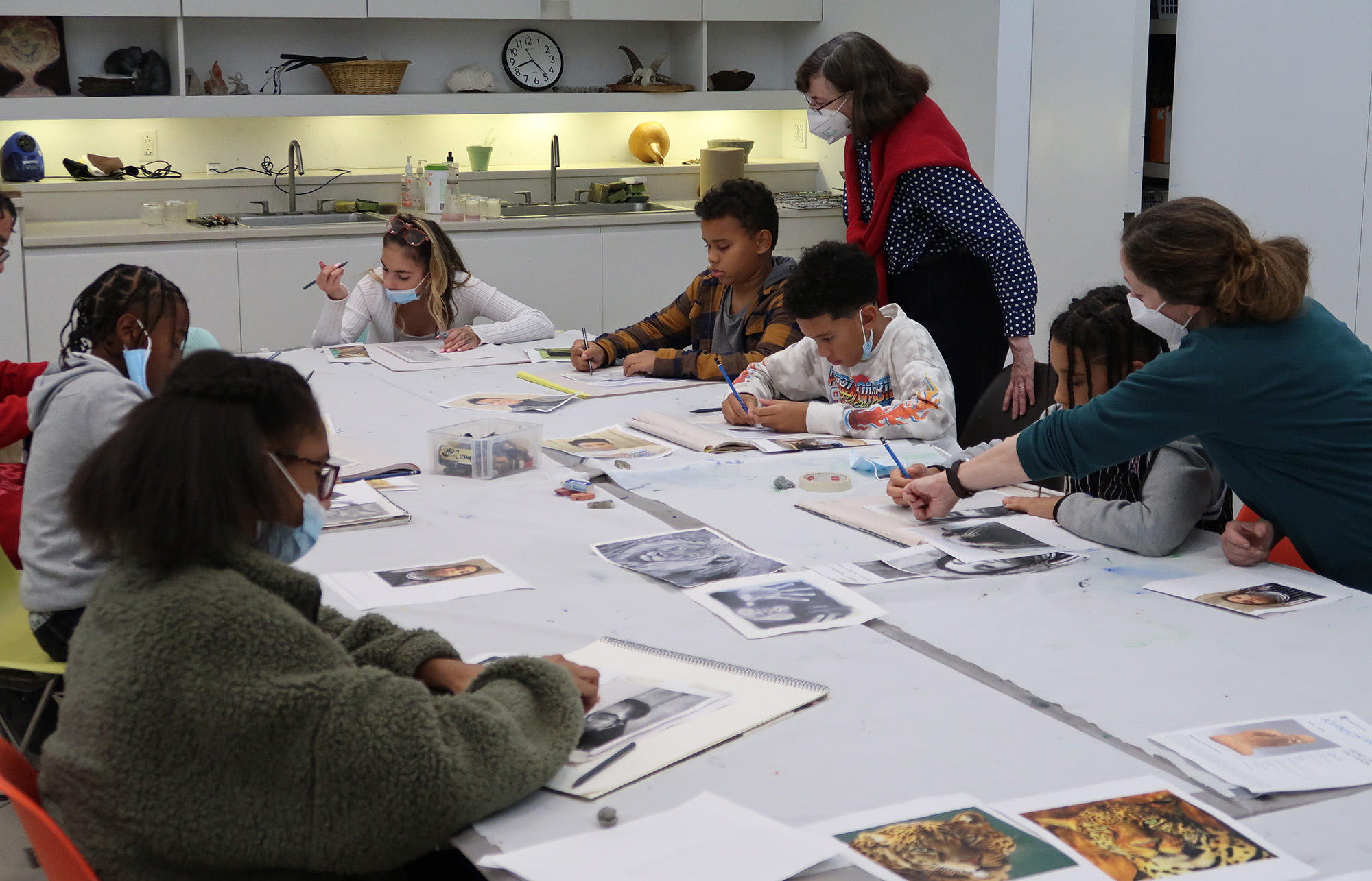 Adults lead children in an art activity around a large table