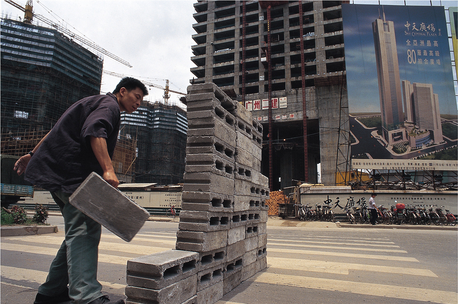 A man stacks concrete blocks on a city road