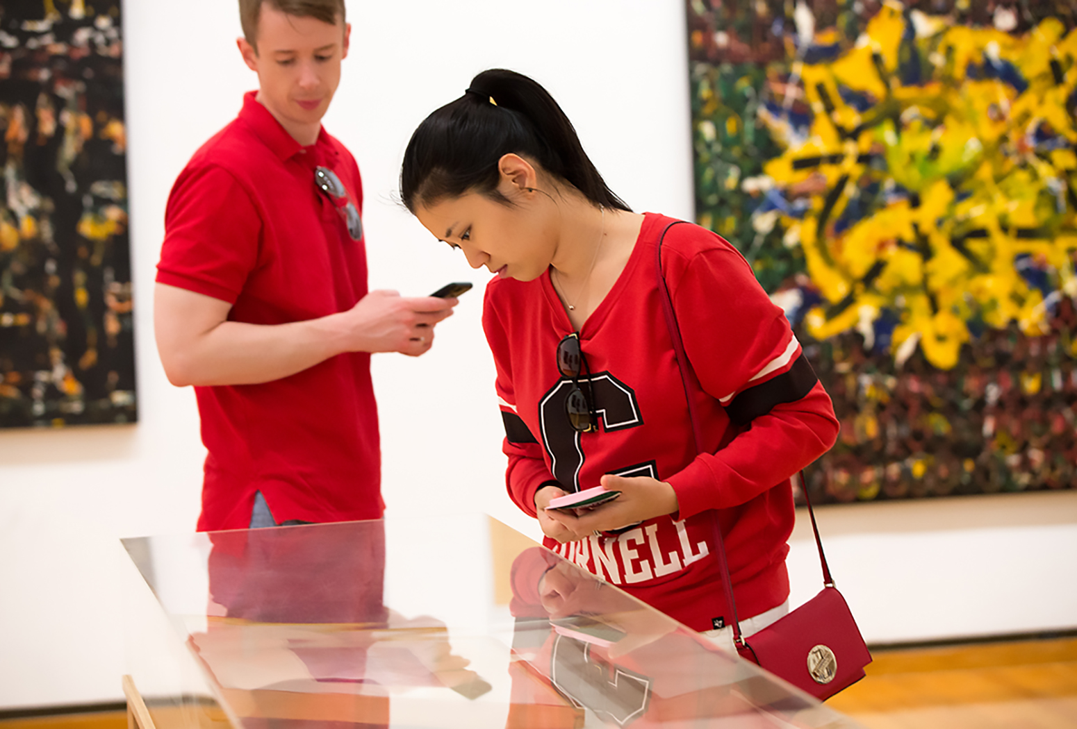 A man and woman in red shirts look at art in a gallery