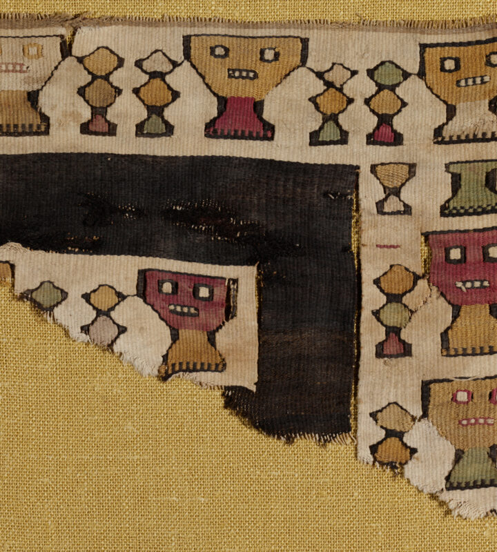 A fragment of a fringed brown textile with figures and geometric shapes dyed in different colors