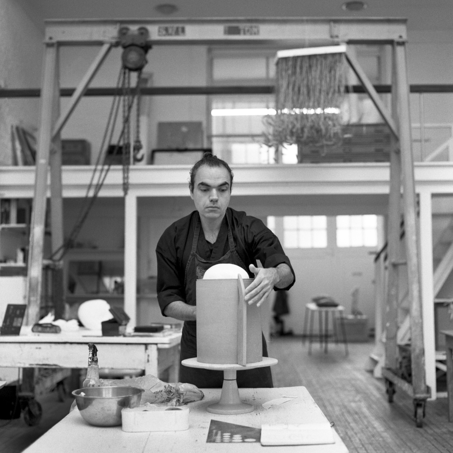 A black and white photo of artist Shahpour Pouyan in his ceramics studio