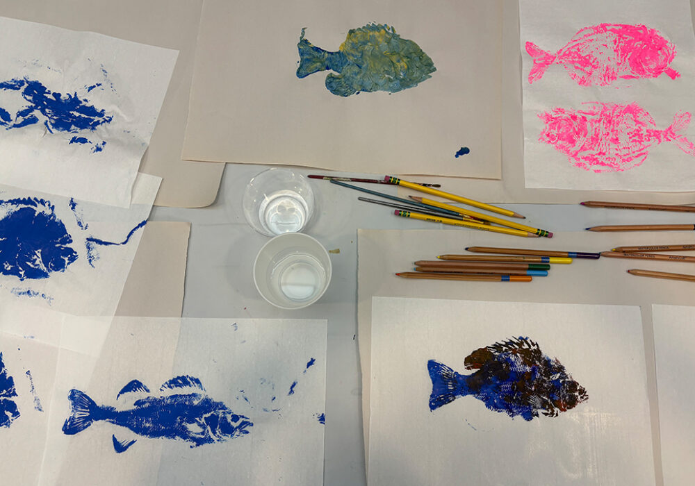 Colorful renderings of painted fish on a workshop table