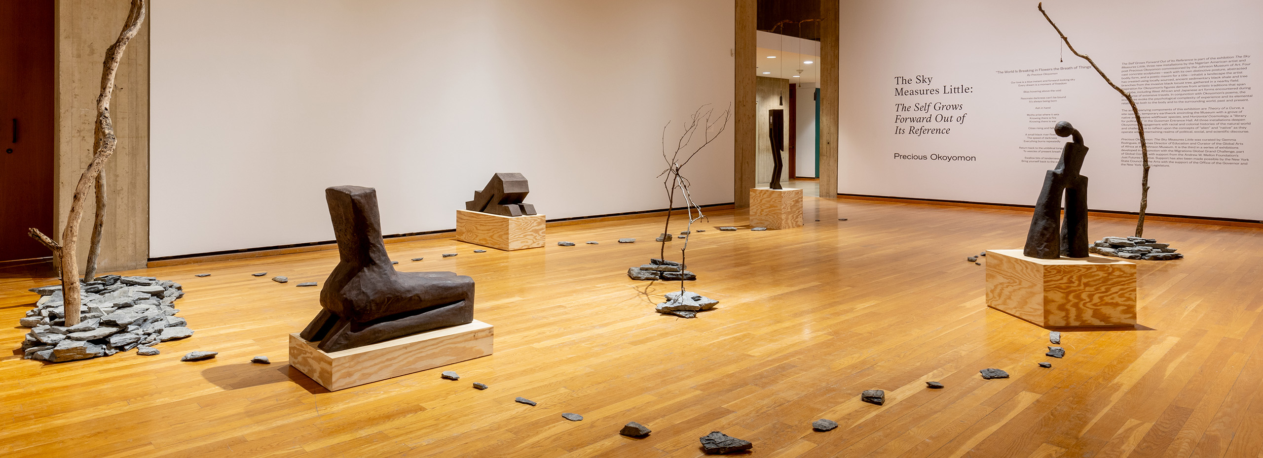 A large gallery with several concrete abstract sculptures, tree branch sculptures, and slate rocks