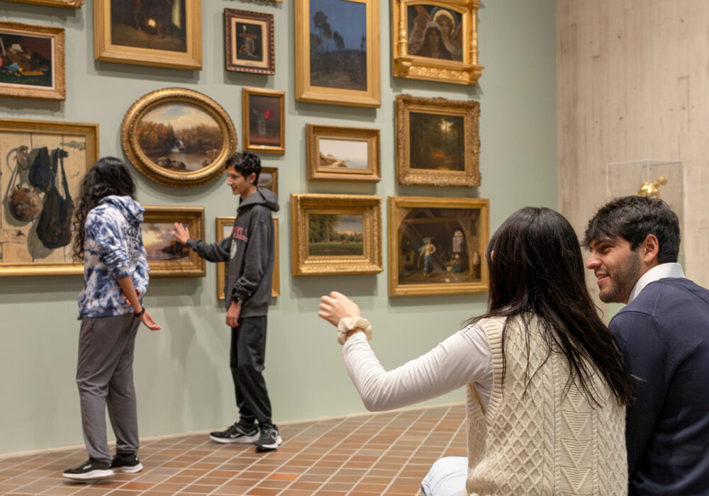 People in a museum gallery looking at many paintings