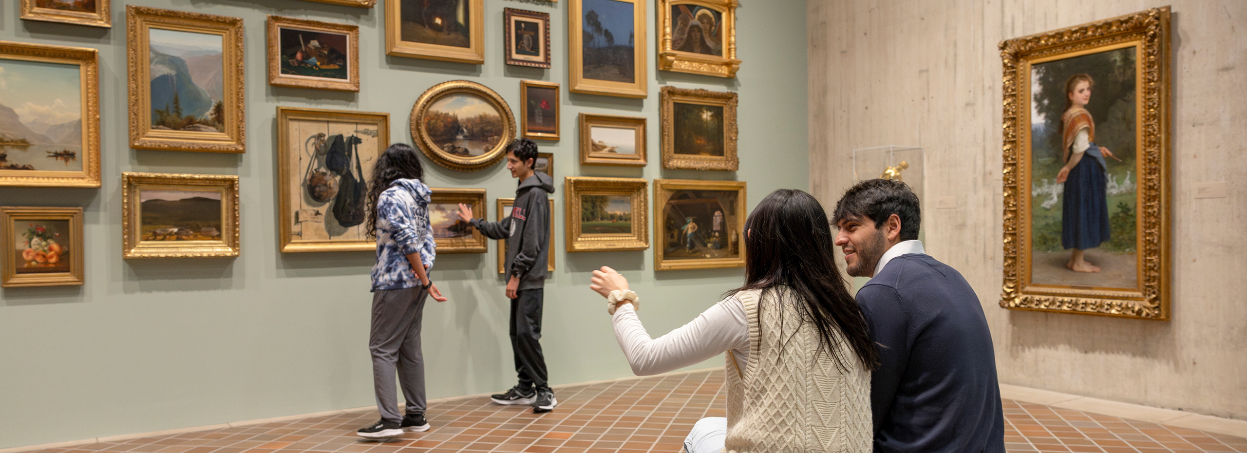 People in a museum gallery looking at many paintings