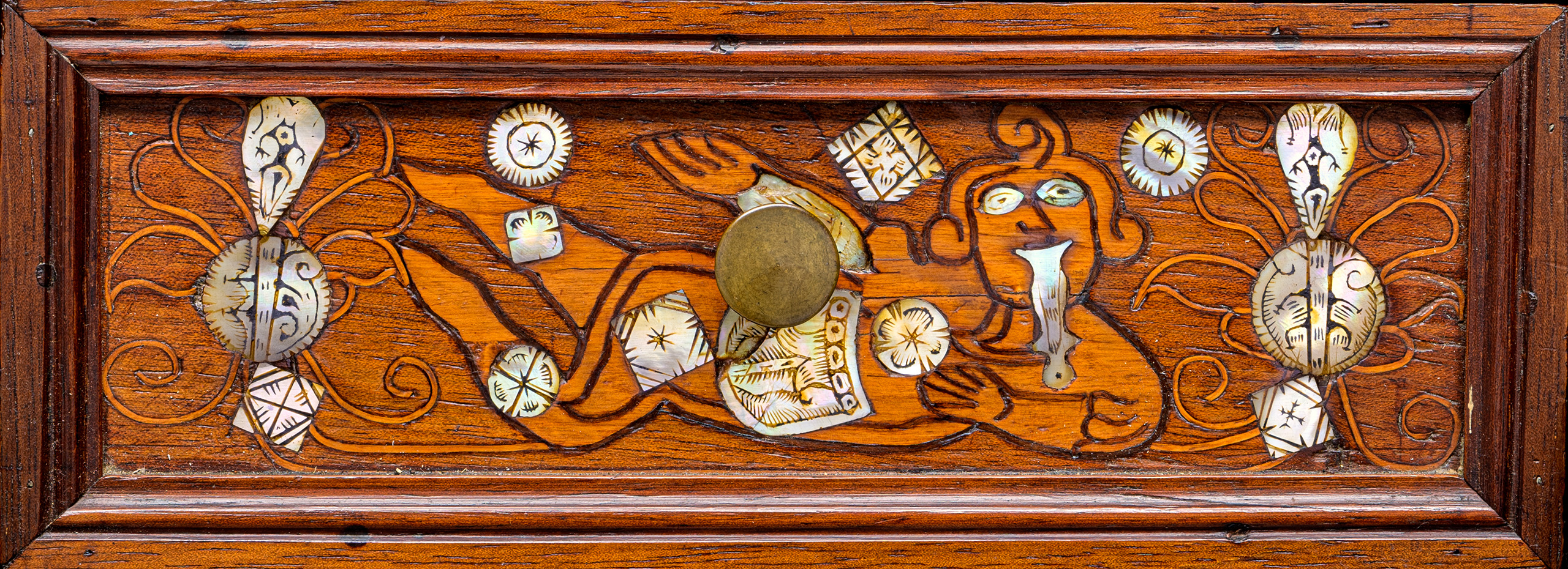 A carved wood drawer from the 18th century with decorative mother-of-pearl and bronze details