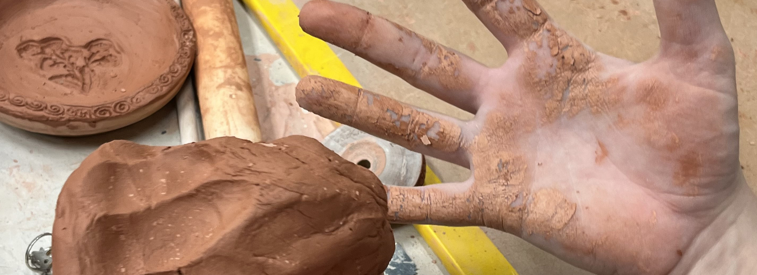 An open hand shows the grime of having worked with hand-built clay in a studio