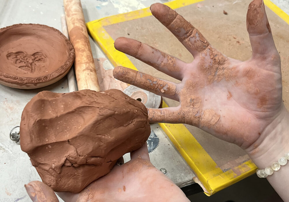 An open hand shows the grime of having worked with hand-built clay in a studio