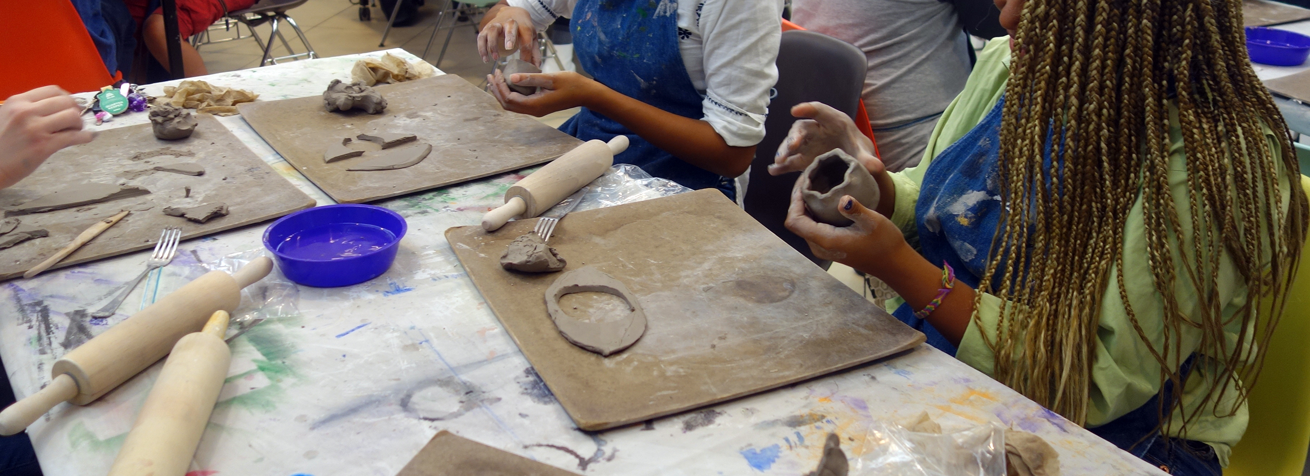 Students make clay sculptures with their hands at a studio table