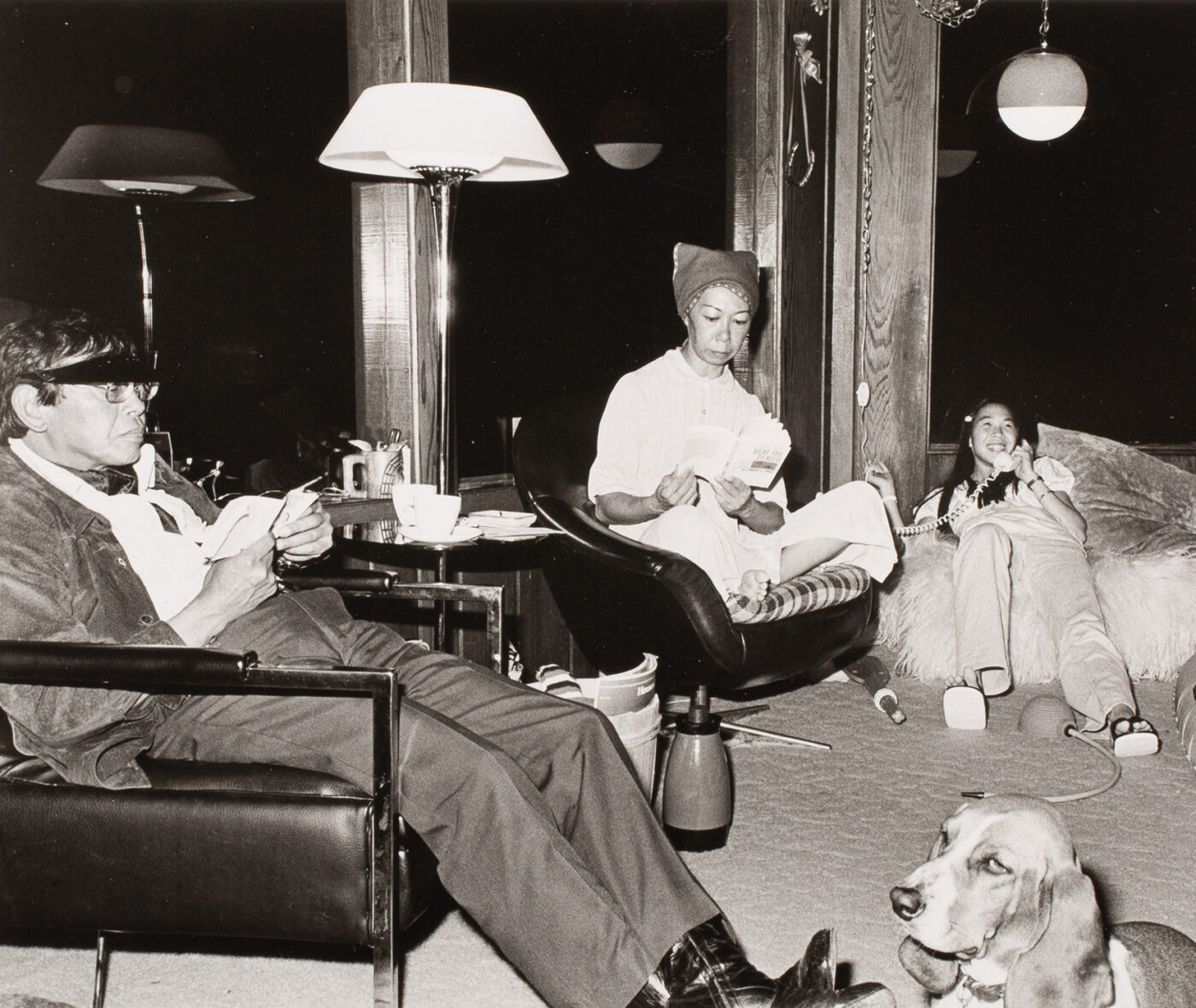 A black and white photo of a man, woman, dog, and child sitting in a living room at night