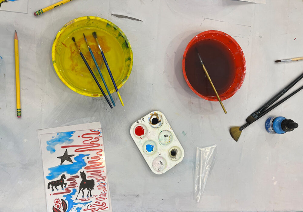 Watercolor painting supplies on a table with a white tablecloth