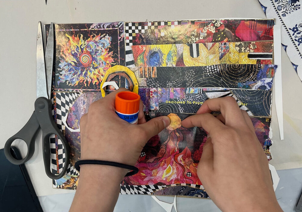 Hands work on a collage project with a glue stick