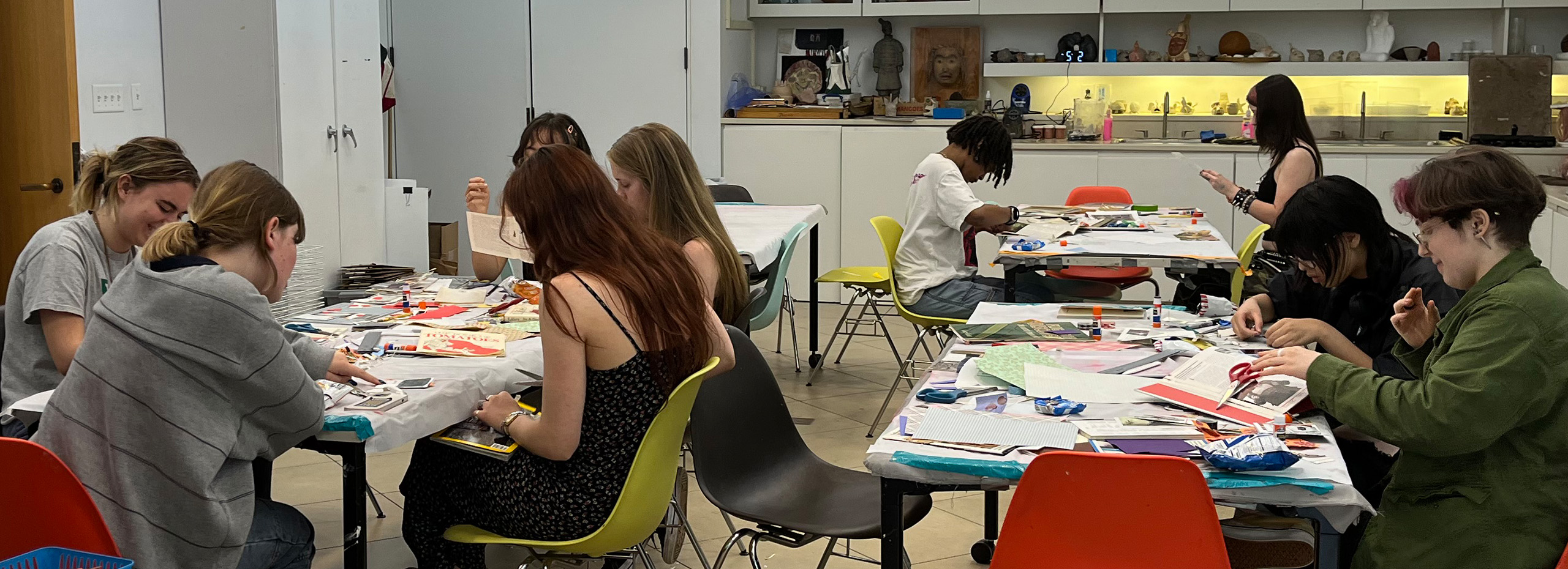 Students gather around studio tables to work on an art project