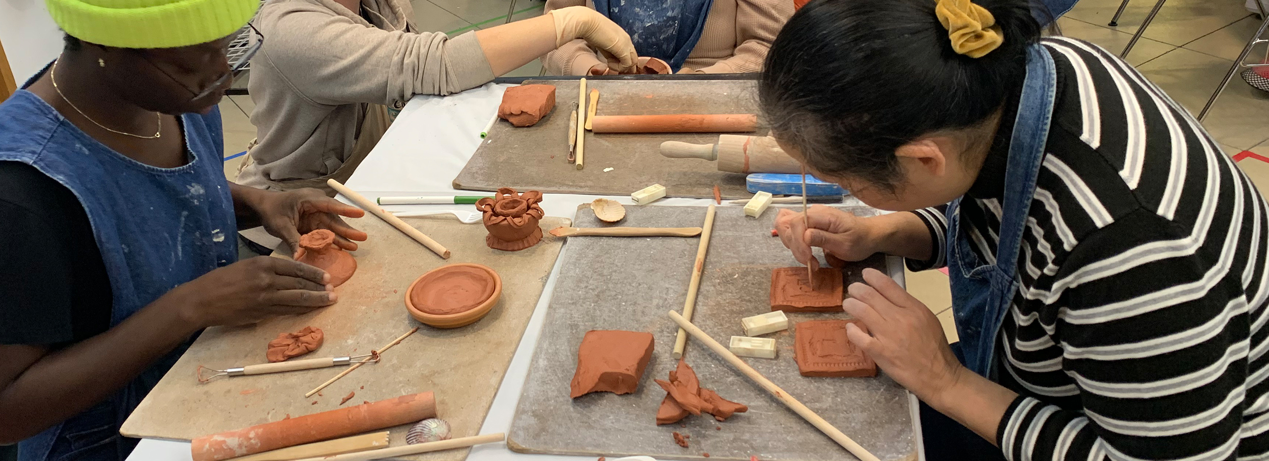 People work on small ceramic sculptures at a table