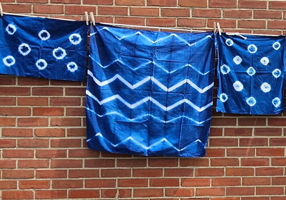 A clothesline of blue and white garments hangs against a brick wall