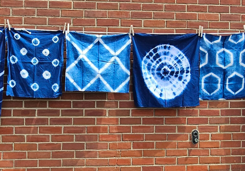 A clothesline of blue and white garments hangs against a brick wall