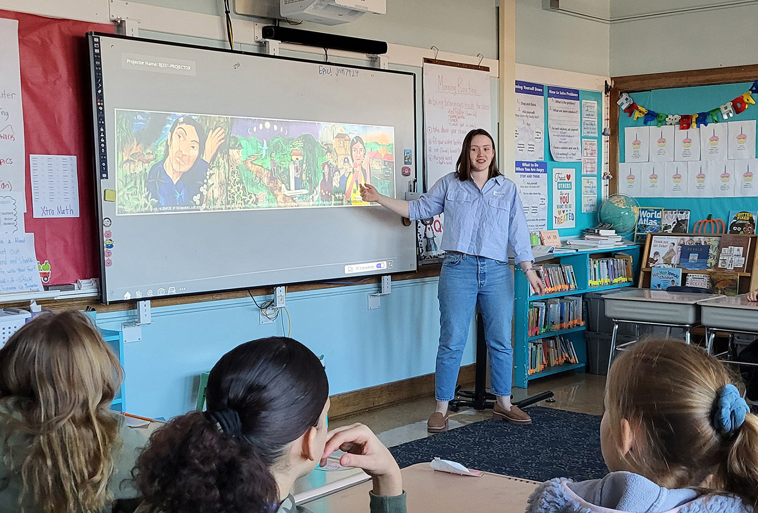 A woman teaches with a projected image in an elementary school classroom