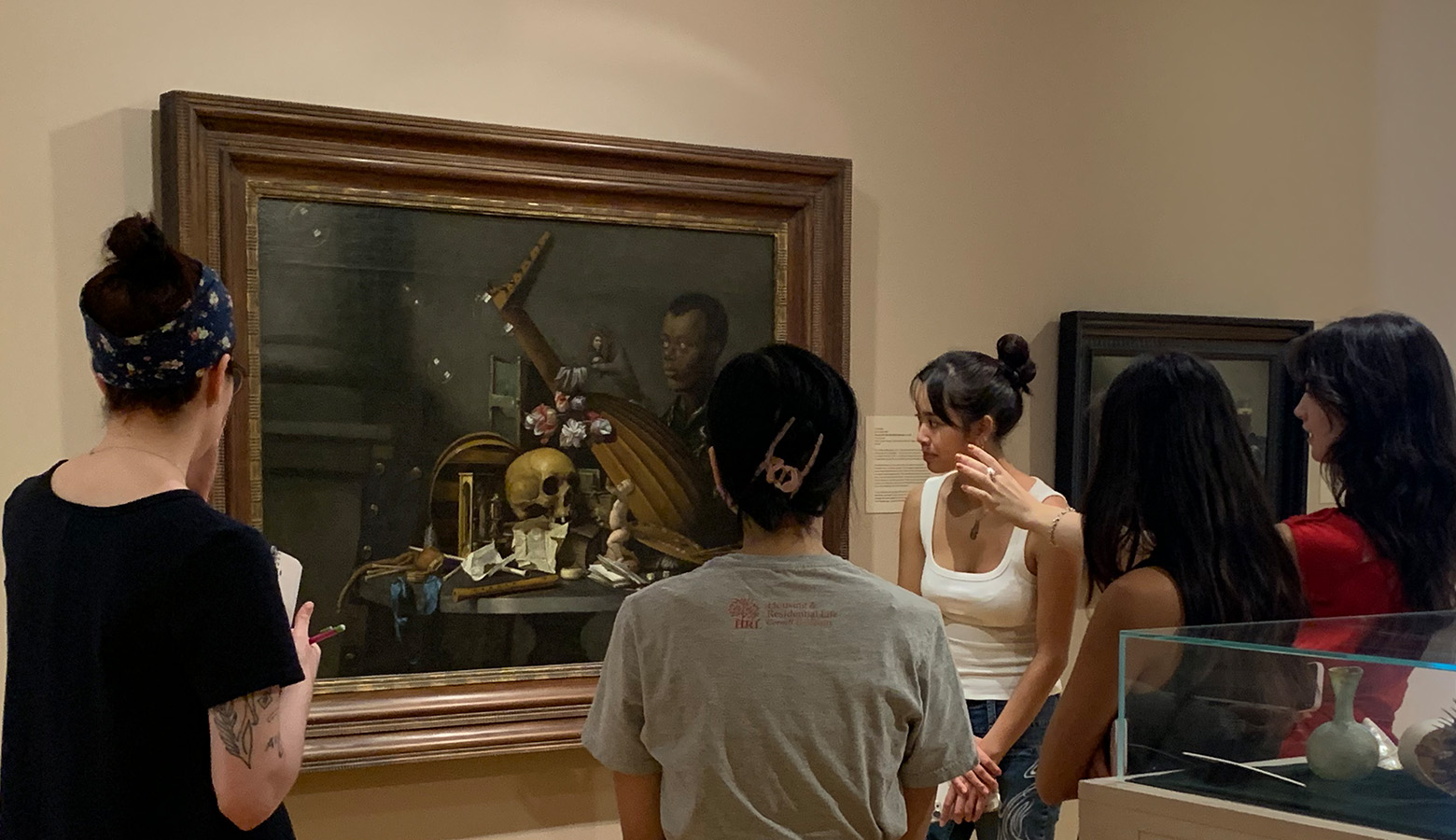 A group of women look at a large oil painting in a gallery