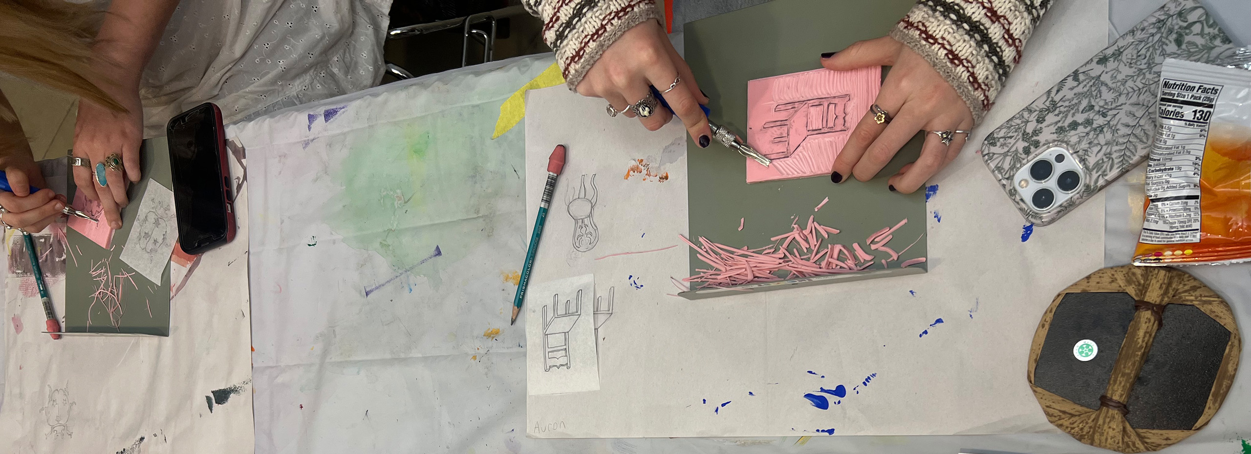 Hands work on an artistic project at a studio table