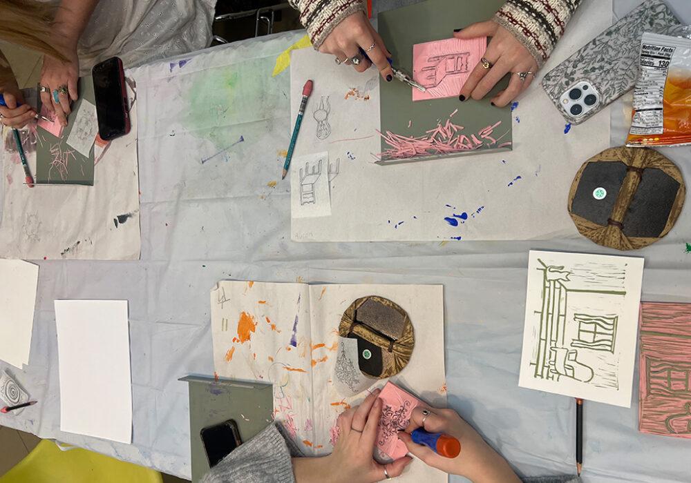 Hands work on an artistic project at a studio table