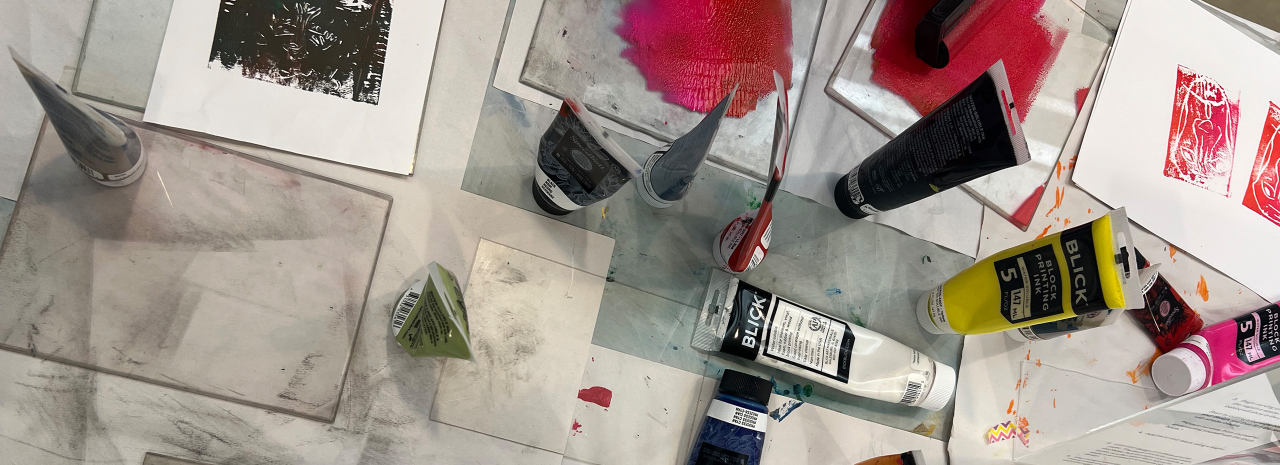 Tubes of red and black paint on a messy studio table