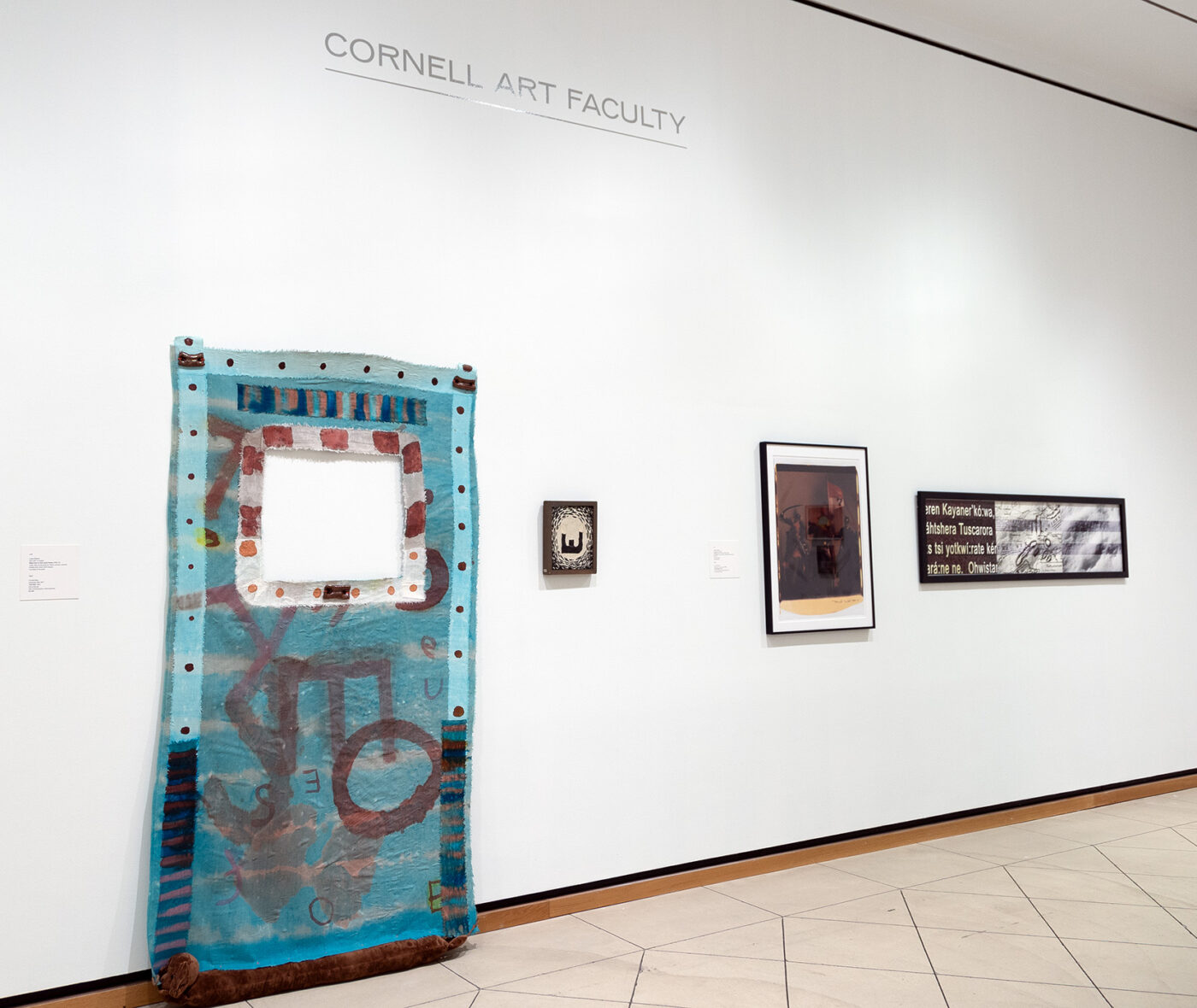Four artworks hang on a white wall