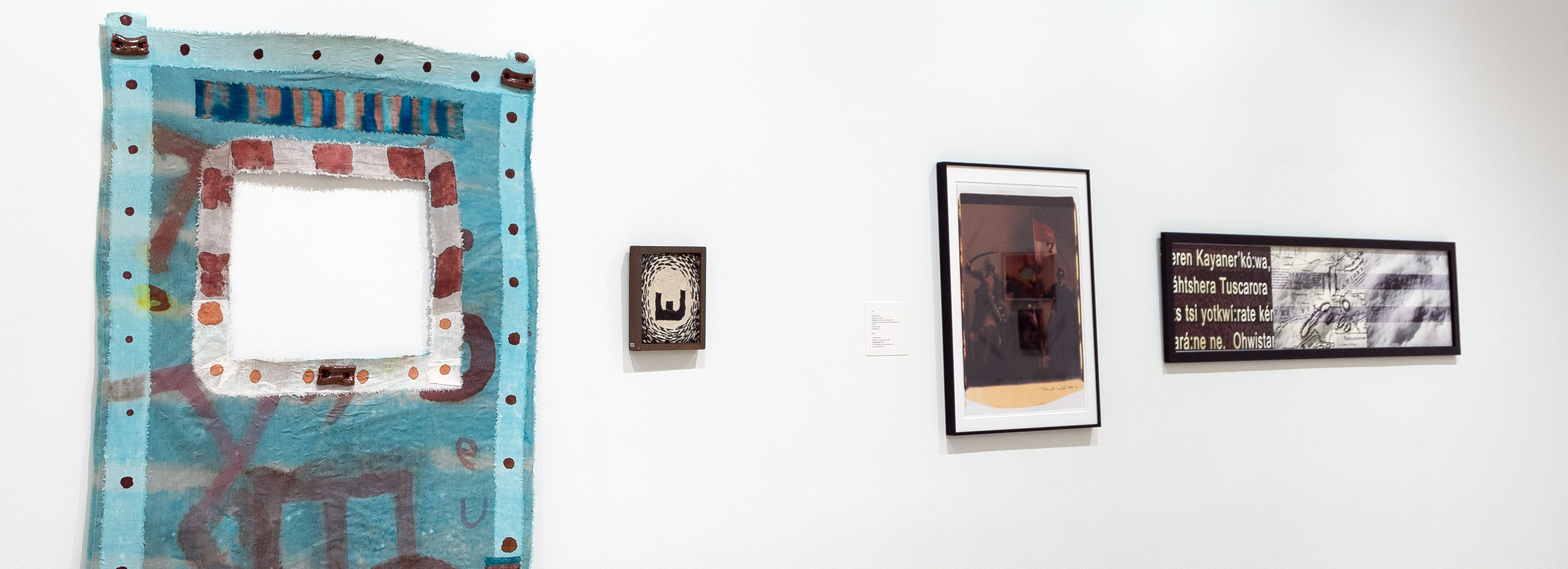 Four artworks hang on a white wall