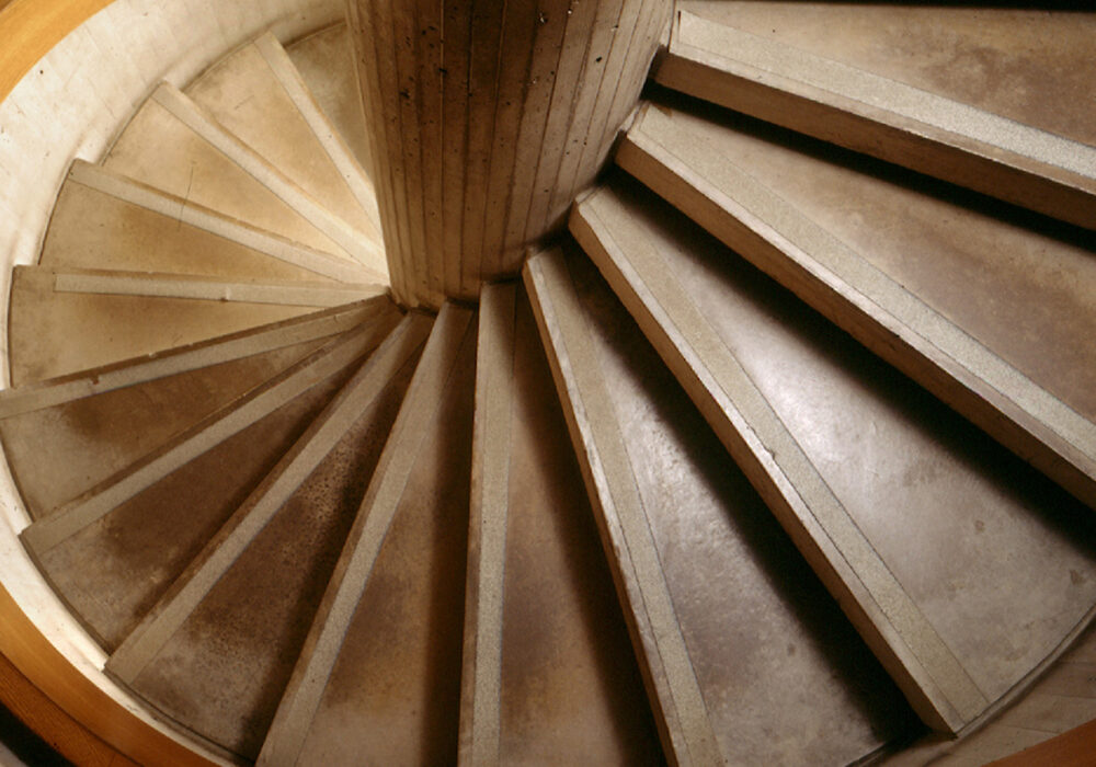 Looking down a concrete and wood spiral staircase