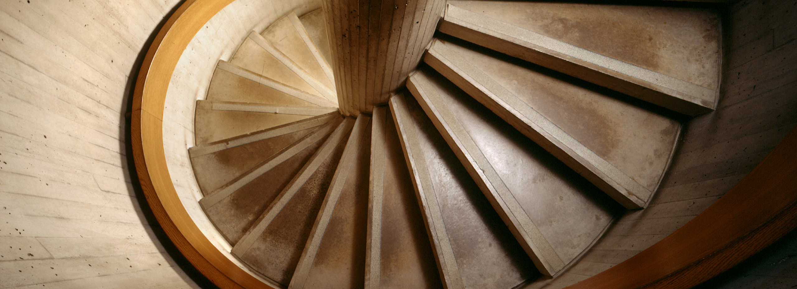 Looking down a concrete and wood spiral staircase