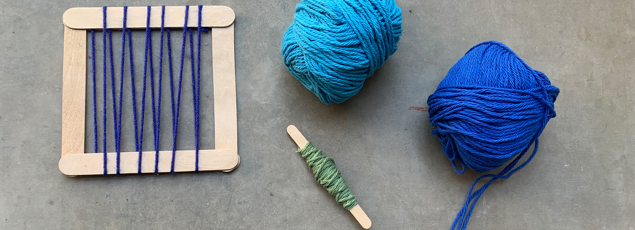 Tools for weaving including blue yarns, a spindle, and a popsicle-stick loom