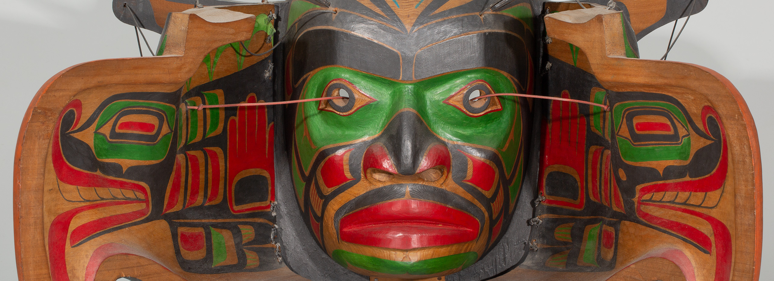 A mask made of carved and painted wood depicting human and bird faces