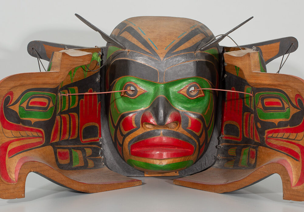 A mask made of carved and painted wood depicting human and bird faces