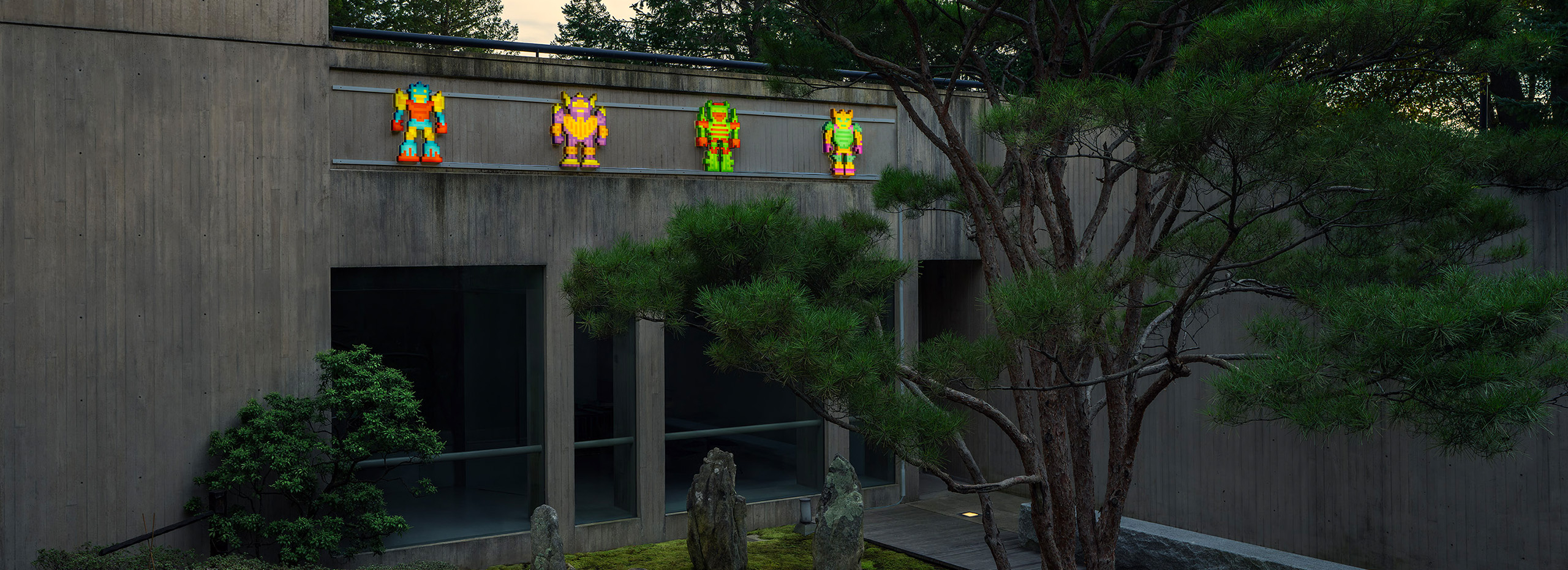 Four colorful pixelated figures are placed above a Japanese garden with a tall tree